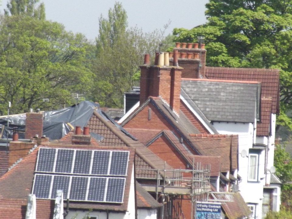 Solar panels on one roof among the chimneys and tiled roofs of an English street