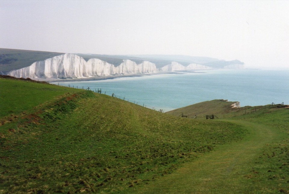 The Seven Sisters chalk cliffs seen across grass downland on the East Sussex coast