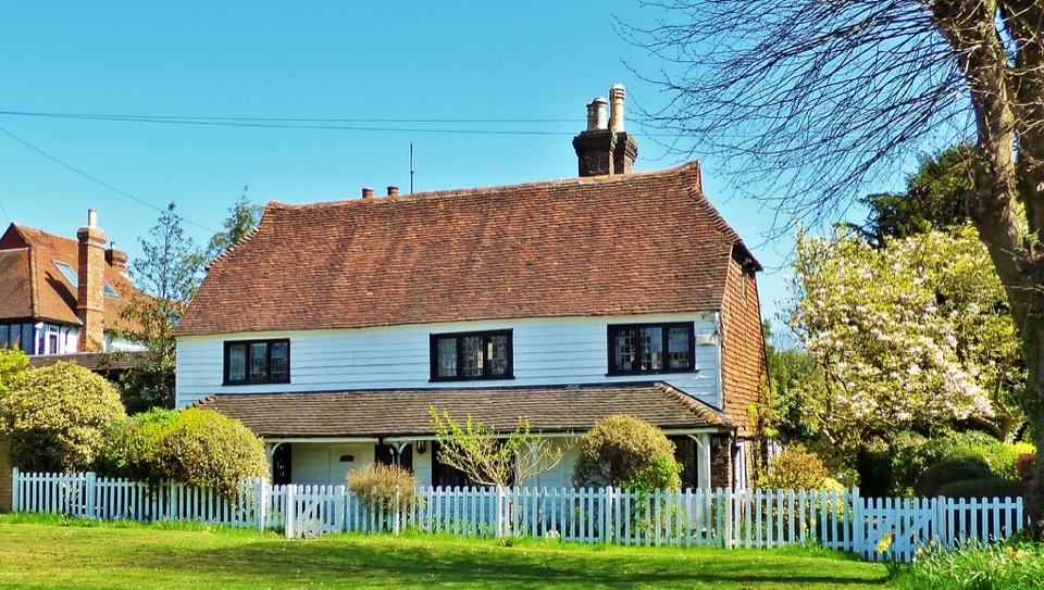 A white weatherboarded house behind a picket fence with an open lawn in front at Southborough in Kent